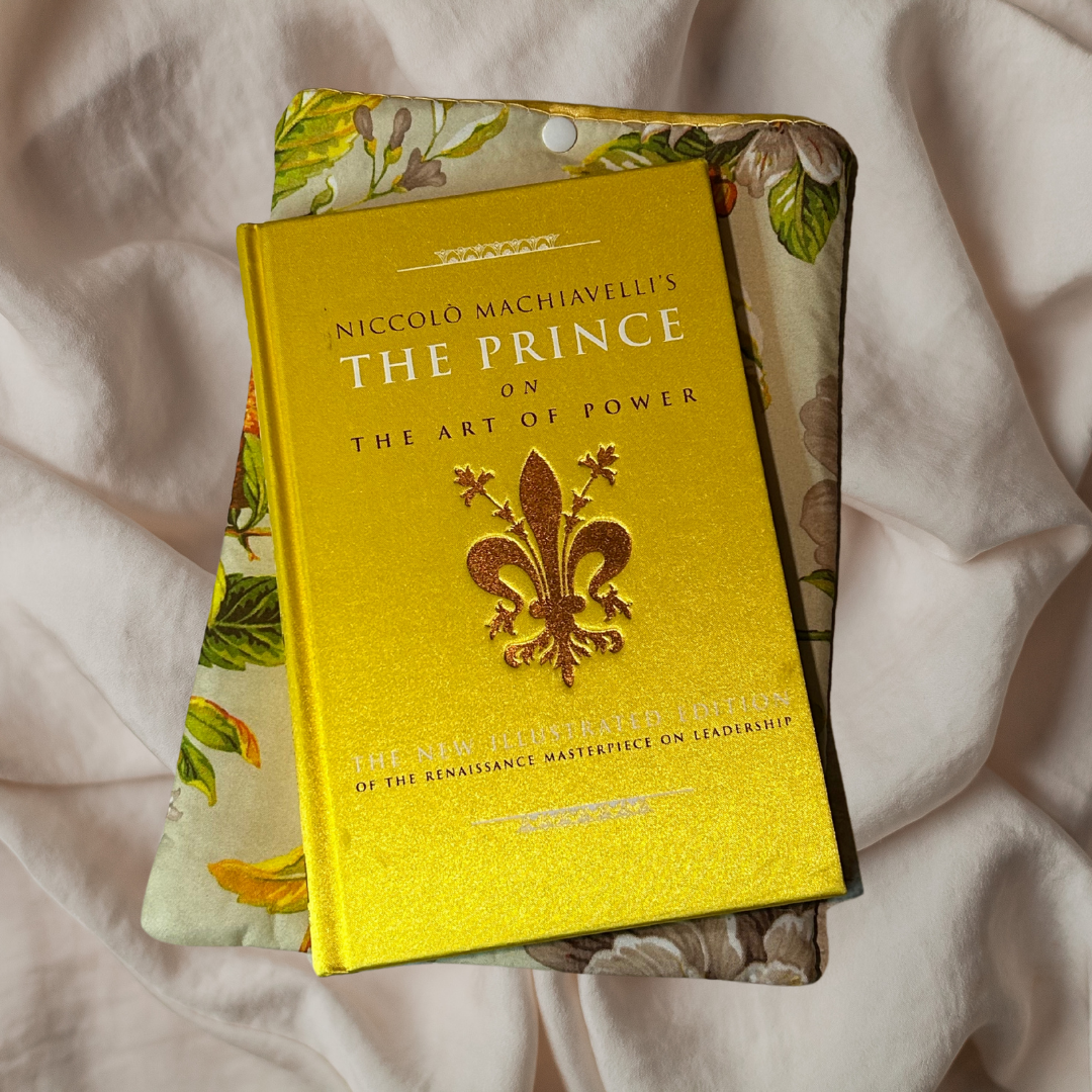 Book titled 'The Prince on the Art of Power' by Niccolo Machiavelli with a decorative cover on a light fabric background.